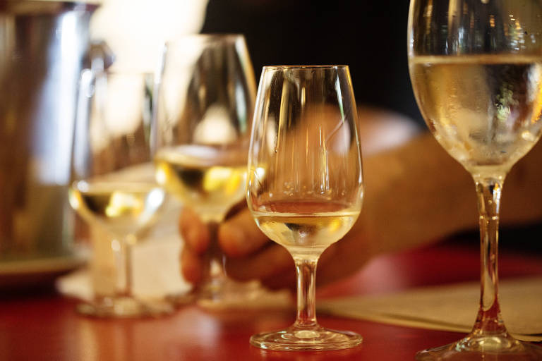 Taças transparentes de vinho são vistas em cima de mesa vermelha