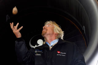 FILE PHOTO: Virgin Group chairman Branson throws a babassu nut in front of a Virgin Atlantic Boeing 747 aircraft, before the world's first commercial biofuel flight to Amsterdam from London