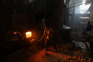 A labourer loads briquettes made out of mustard husk into a furnace at a dyeing unit in Panipat