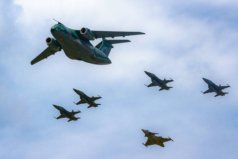 Um Embraer KC-390 voa escoltado por quatro caças F-5 e um Gripen (atrás) da FAB
