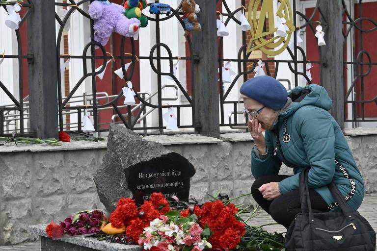 Ucraniana visita memorial perto de estação de trem em Kramatorsk, na região de Donetsk, local onde há um ano ataques com mísseis russos deixaram dezenas de civis mortos