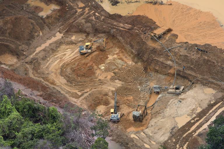 Vista área de máquinas escavando terra em área desmatada