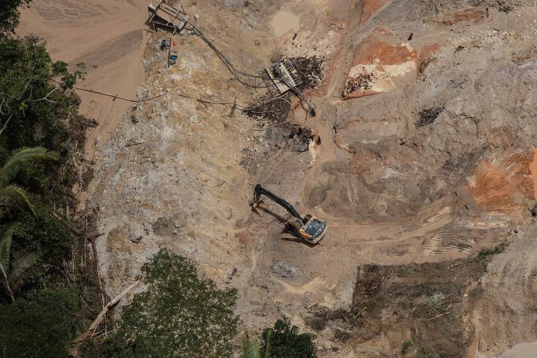 Imagem aérea de máquinas cavando terra em área de garimpo