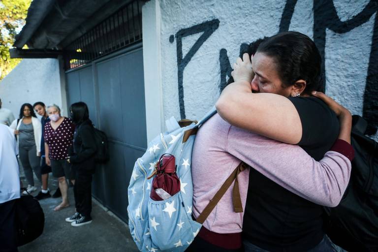 Estudante de mochila abraça mulher na porta de escola