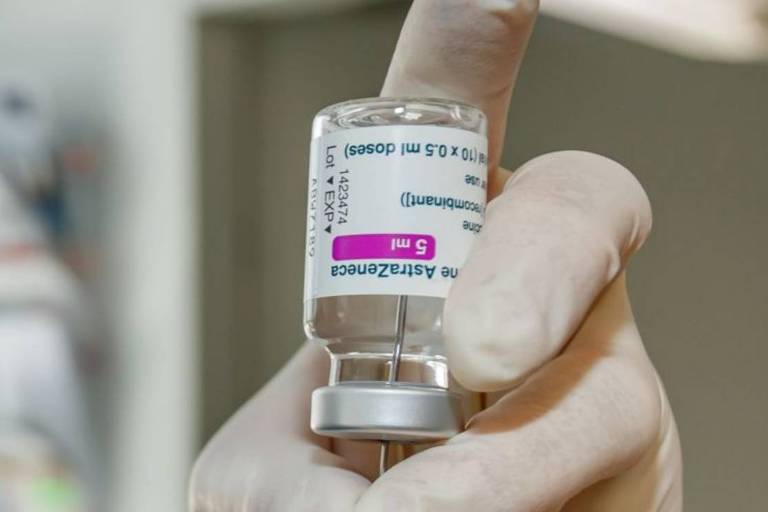 Imagem fechada de um enfermeiro tirando o líquido da vacina de dentro de um vidro com uma seringa