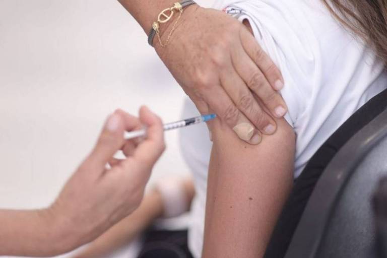Enfermeira aplica vacina no braço esquerdo de uma mulher não identificada