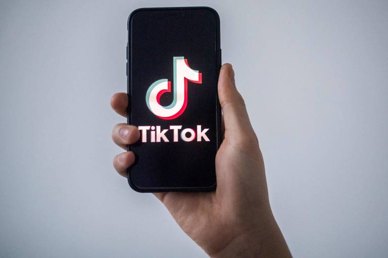 Uma mão masculina segurando um celular com o logotipo do aplicativo TikTok