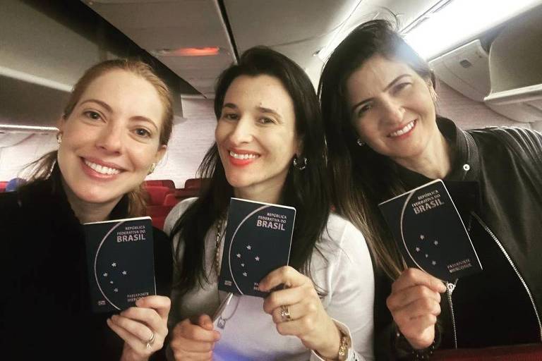 luna, jeanne e kátyna posam para foto, sorriem e seguram passaportes brasileiros na mão