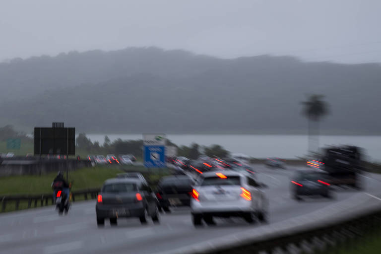 foto mostra carros transitando por estrada em dia de chuva 