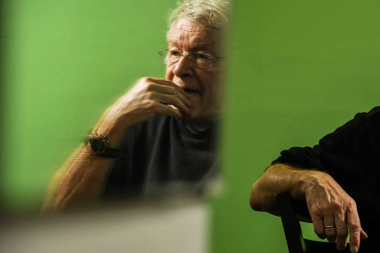 foto espelhada de homem idoso com camisa preta contra fundo verde