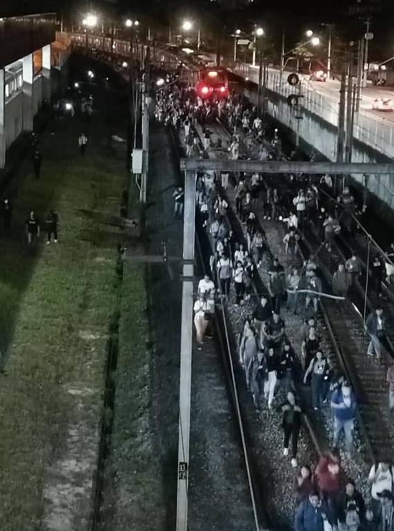Passageiros descem de trem entre as estações Tatuapé e Itaquera, na zona leste de São Paulo, para seguir a pé pelos trilhos, após ficarem parados por mais de uma hora