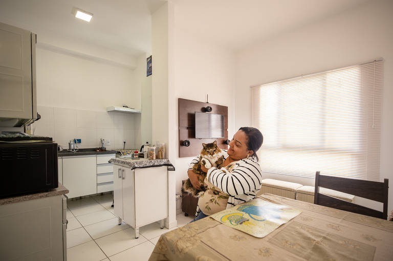 A copeira hospitalar Adriana de Abreu Fester, 48 , com seu gato na sala do novo apartamento. Ela e o marido foram os primeiro a se mudar após inauguração do condomínio.