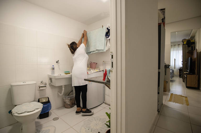 Francisca de Jesus D'água, 57, estendendo roupas no banheiro e lavanderia do seu apartamento, onde mora com o filho de 15 anos.