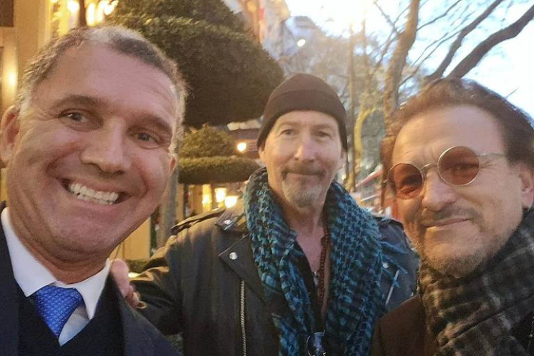 Daniel Lian ao lado de The Edge e Bono, integrantes do U2