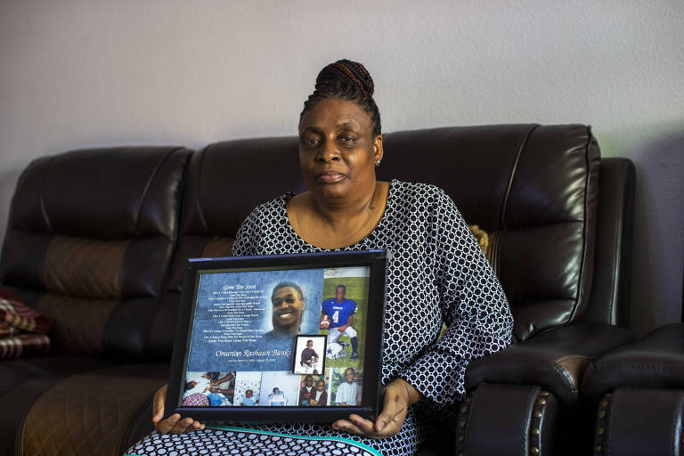 Lisa Johnson-Banks holds a framed memorial of her son, Omarian Banks