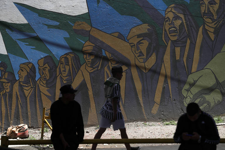 Homem caminha perto de mural em Buenos Aires, na Argentina, ao lado de protesto contra corte em planos de assistência social durante grave crise econômica