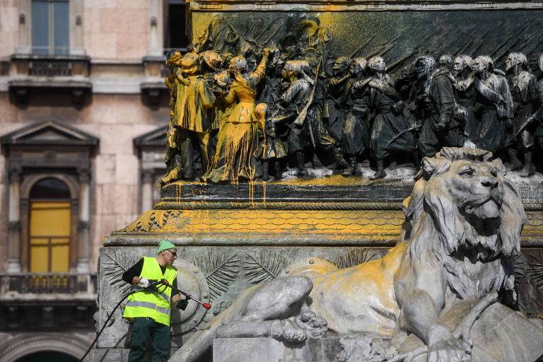 Funcionário limpa estátua do rei Vittorio Emanuele 2º, em frente ao Duomo de Milão, manchada por ativistas ambientais na Itália