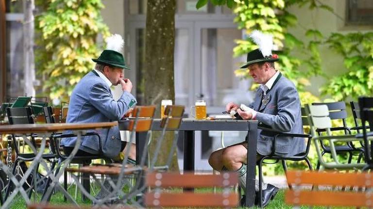 Dois homens de meia idade tomam cerveja em uma mesa