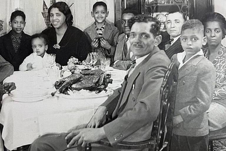 Família sentada ao redor da mesa em uma foto em preto e branco