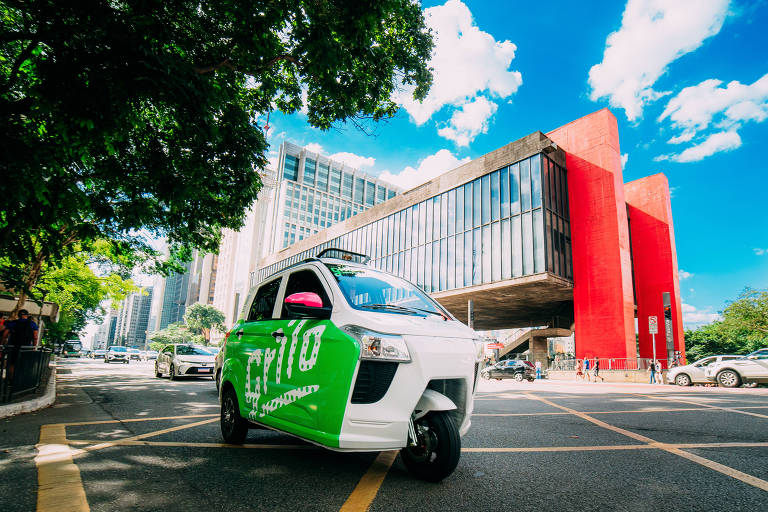 Triciclo com cabine fechada e carroceria branca e verde, em frente ao Museu de Arte de São Paulo (Masp)