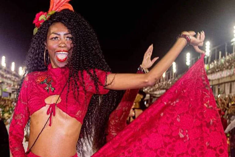 Imagem colorida mostra Alessandra Silva, de 35 anos, caracterizada como passista no Sambódromo do Rio de Janeiro. Ela é negra e usa uma roupa vermelha.