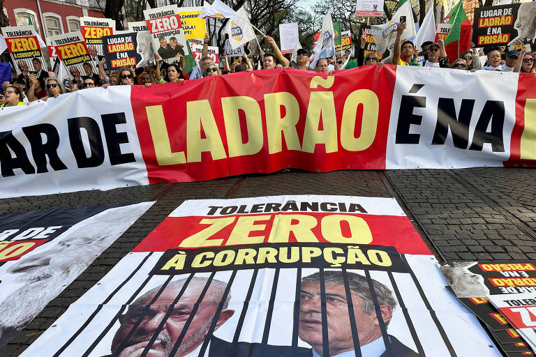 Manifestantes contra Lula protestam com cartazes que o chamam de ladrão e corrupto em frente ao Parlamento de Portugal, em Lisboa, onde o presidente discursava 
