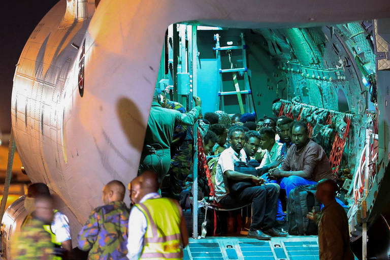 Pessoas que fugiram do Sudão aguardam em avião militar na cidade de Nairobi, no Quênia