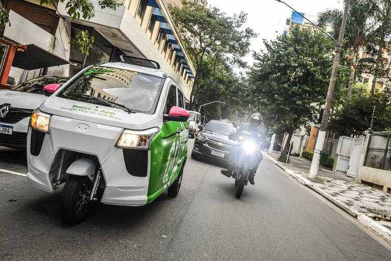 Triciclo elétrico é ladeado por moto em rua do centro de São Paulo