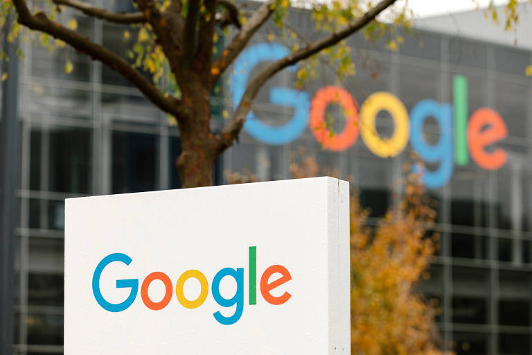 O campus do Google em Mountain View, Califórnia, em 4 de dezembro de 2019. Em primeiro plano, está um totem branco com o logo do Google. Atrás, há uma árvore e um prédio espelhado com o logo da empresa.