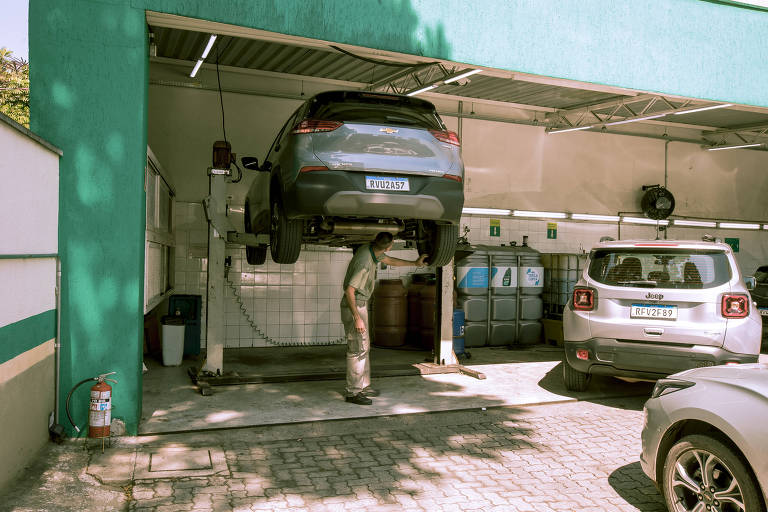 Foto mostra área do serviço de manutenção no pátio da Localiza, nos arredores do aeroporto de Congonhas, em São Paulo; um carro está suspenso e um mecânico observa a parte inferior do veículo