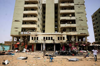 A man walks past near a damaged car and buildings at the central market in Khartoum North