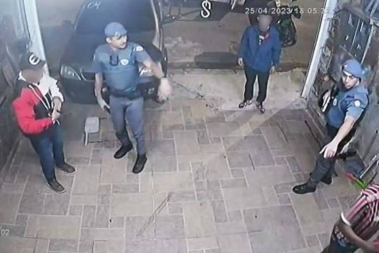 Dois policiais militares, com armas em punho, abordam moradores dentro de garagem