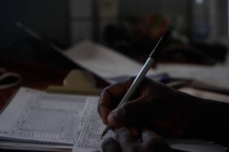 Mão de uma pessoa negra escreve no caderno