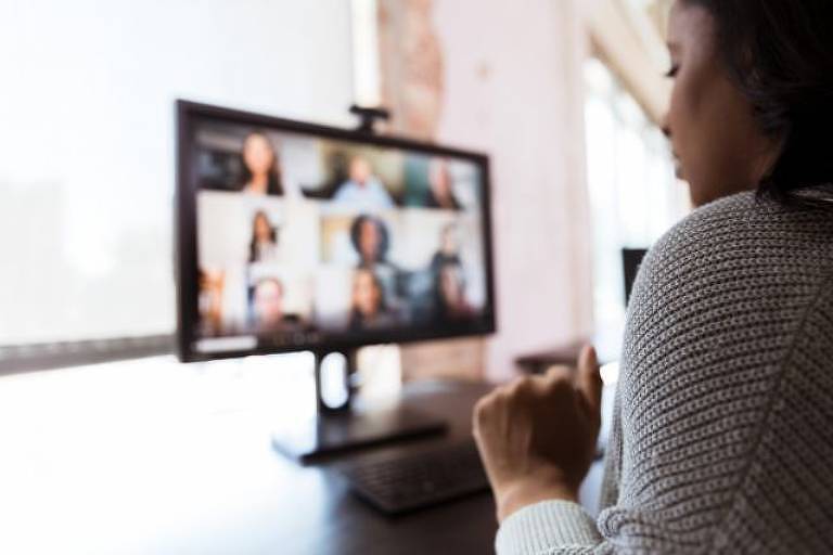 Mulher observa um monitor que mostra várias pessoas em uma videoconferência