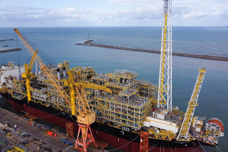 Vista aérea da plataforma de petróleo em um porto, com grandes gruas montando estruturas