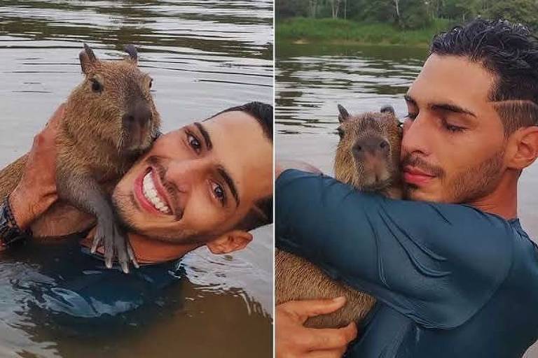 Em foto colorida, homem aparece com capivara nadando em um rio