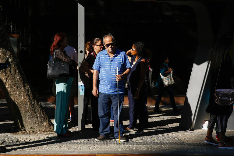 Homem cego aguardo em ponto do sistema de VLT, no Rio de Janeiro