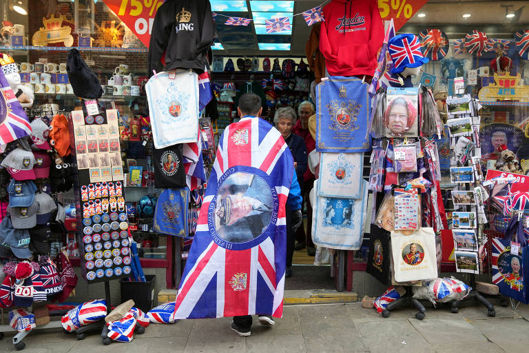 Mulher carrega bandeira do Reino Unido nos ombros em frente a uma loja de souvenirs
