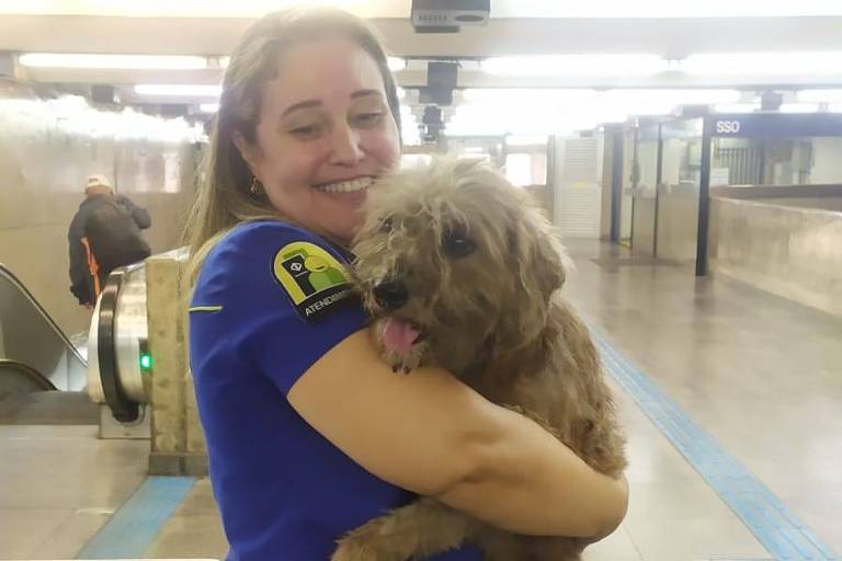 A operadora de transporte metroviário Katia Santana segura cachorro em frente a catraca do metrô