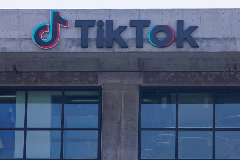 Fachada de escritório do TikTok em Culver City, California. O prédio tem estrutura de concreto, com duas janelas de esquadrias metálicas pretas, separadas por um pilar. Na viga superior, há o logo do TikTok, seguido do nome da empresa.