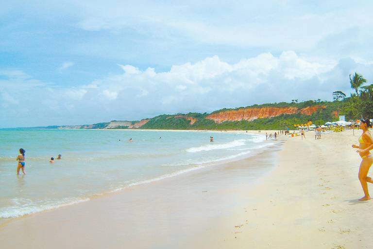 Praia de Pitinga, em Arraial d'Ajuda, no sul da Bahia. Em um dos lados, um paredão de falésias (ao fundo) contrasta como azul claro das águas