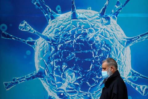 FILE PHOTO: A man wearing a protective face mask walks past an illustration of a virus outside a regional science centre, as the city and surrounding areas face local restrictions in an effort to avoid a local lockdown being forced upon the region, amid the coronavirus disease (COVID-19) outbreak, in Oldham, Britain August 3, 2020. REUTERS/Phil Noble/File Photo ORG XMIT: FW1