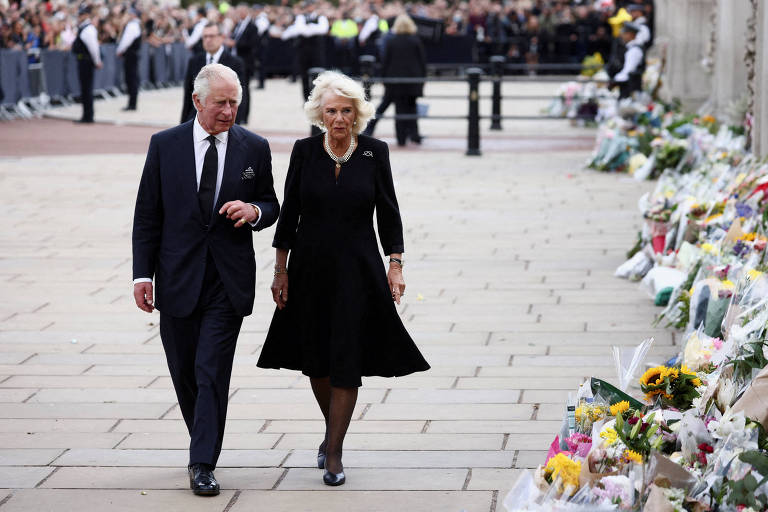 O rei Charles 3º e a em breve rainha Camilla caminham nos arredores do Palácio de Buckingham, em Londres, perto de homenagens à rainha Elizabeth 2ª pouco após sua morte