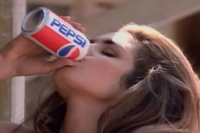 Moça bebe Pepsi em lata com logotipo da empresa