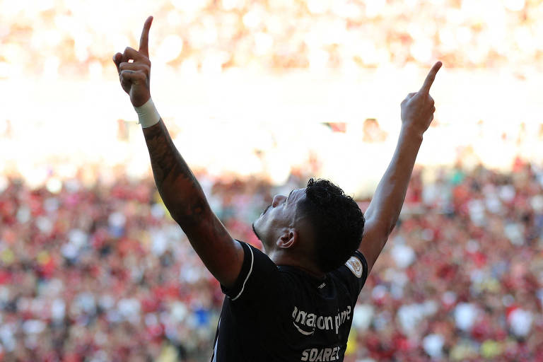 Com os braços abertos e erguidos e os dedos indicadores apontados para o alto, o atacante Tiquinho, do Botafogo, vibra ao fazer gol contra o Flamengo no Maracanã