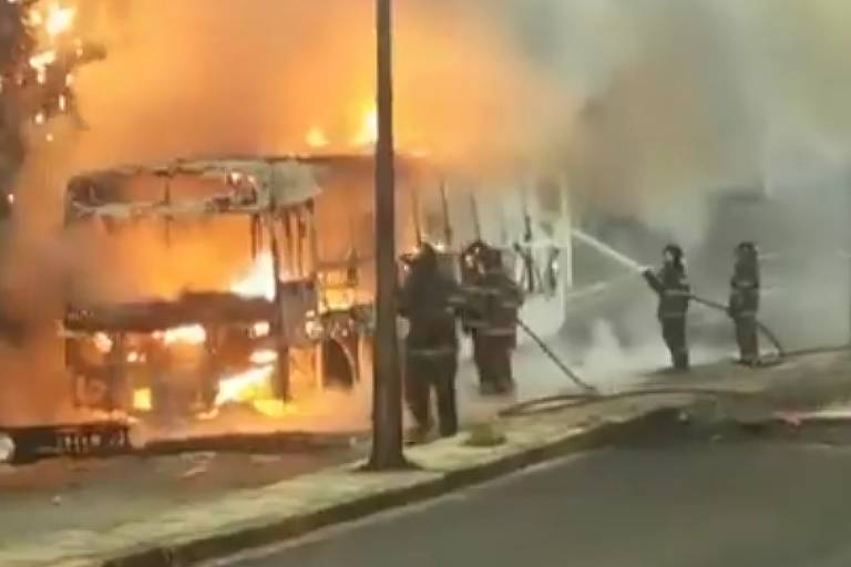 Grupo de bombeiros apagando fogo em ônibus em uma das vias da Avenida Tiradentes, em Guarulhos