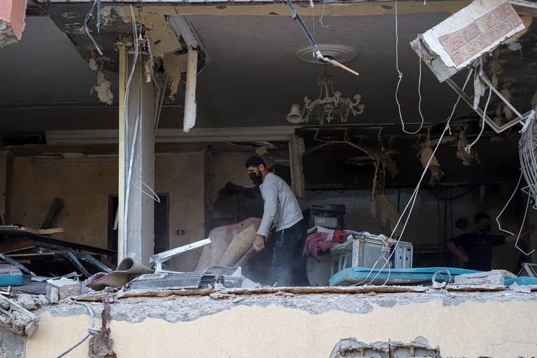 Palestino confere danos deixados em apartamento na Faixa de Gaza após ataques de Israel à região deixarem 13 pessoas mortas