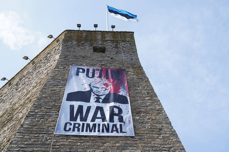 Cartaz em que se lê 'Putin, criminoso de guerra' pendurado na Fortaleza de Narva, parte do Museu de Narva, na Estônia