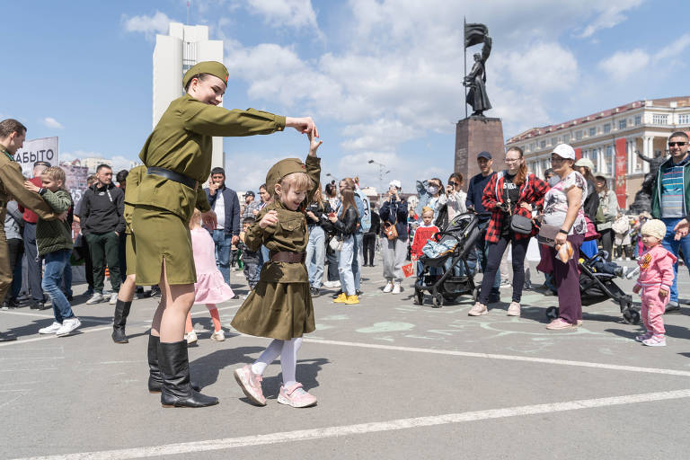 Mulher e menina dançam em uniformes militares soviéticos em evento de celebração do Dia da Vitória em Vladivostok