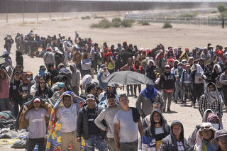 Migrants who have crossed into the U.S. from Mexico line up near the border fence to turn themselves in to Border Patrol in El Paso, Texas, on May 8, 2023. (Todd Heisler/The New York Times)
